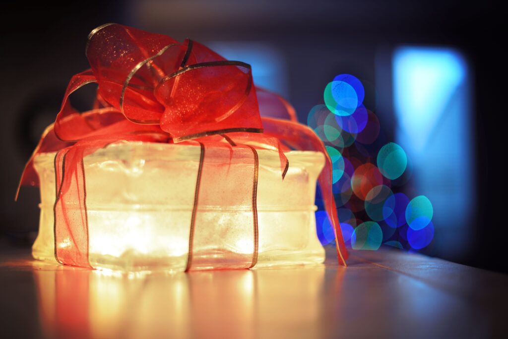Festive gift box with red ribbon and colorful bokeh lights creating a cozy holiday atmosphere.